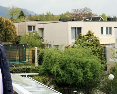 Der Home Energy Kunde Daniel Oetterli steht vor seiner PV-Anlage, im Hintergrund ist eine Wohsiedlung zu sehen.
