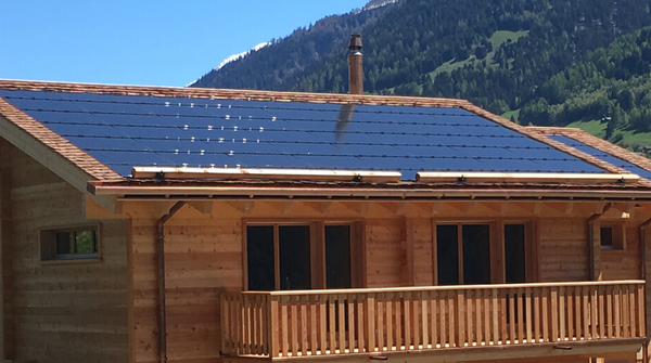 Seitliche Aufnahme eines Holzhauses mit Solaranlage auf dem Dach in Fiesch.