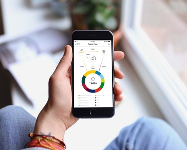 Eine Hand hält ein Smartphone auf dem die Home Energy App geöffnet ist.